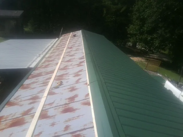 Old rusted panels beside newly installed green metal roofing — Wind Damage Roof Repair by Roofing Brothers in West Babylon