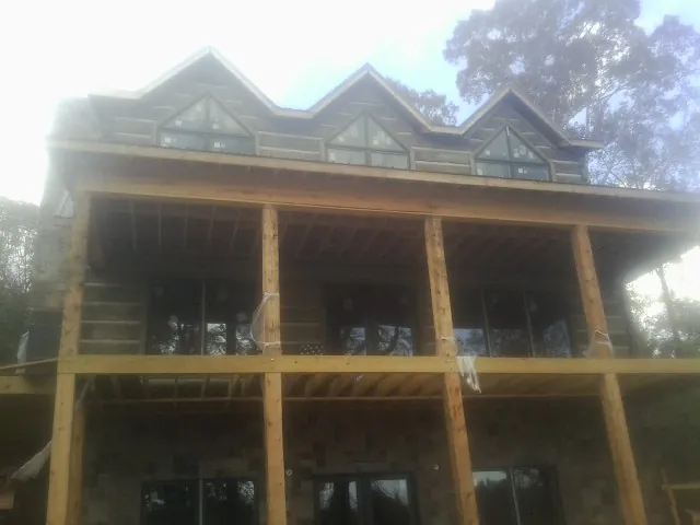 Dormers and porch framing on a large log home under construction — Roof Coating work by our crew in West Babylon