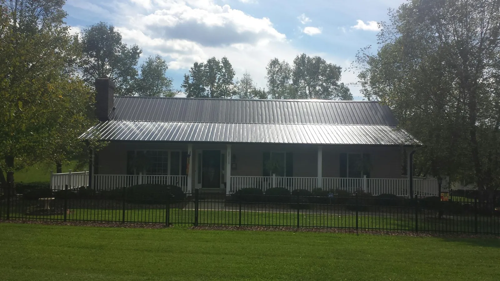Gray metal roof on a brick ranch with a full width front porch — Gutter Guard Installation work by our crew in West Babylon