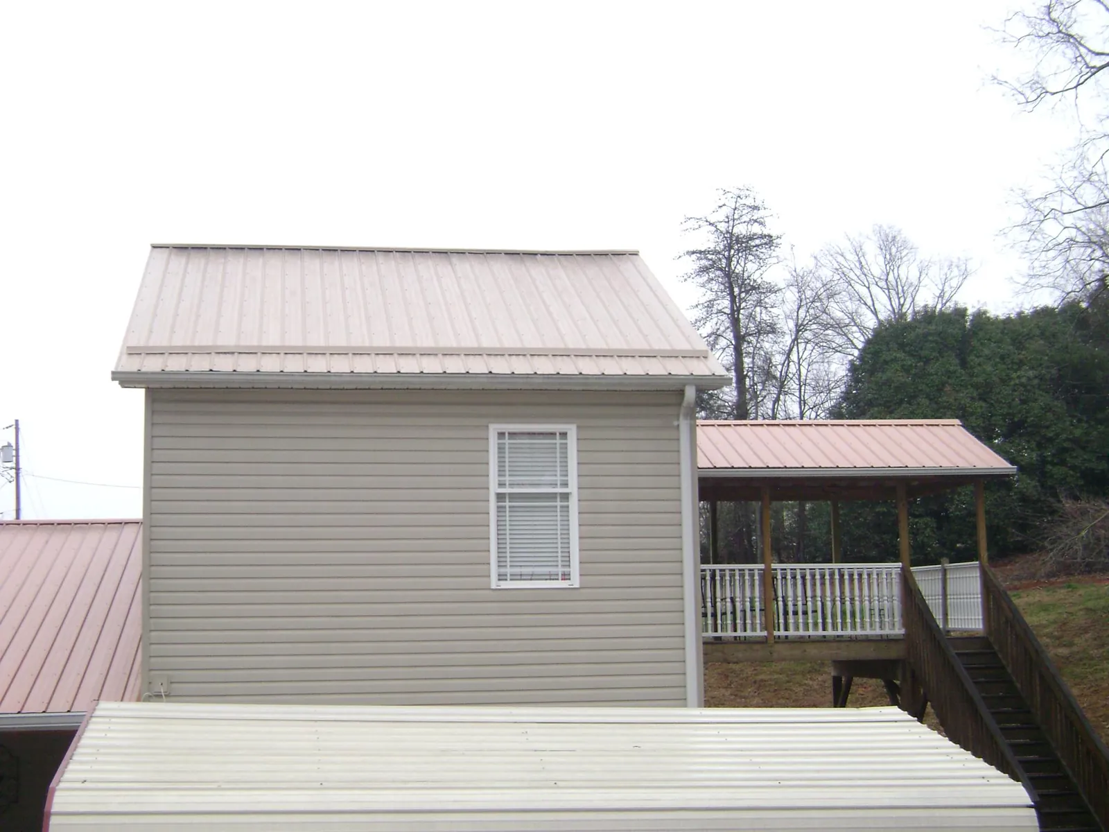 Tan metal roofs on a two story addition and attached porch, from a Roof Replacement job in West Babylon