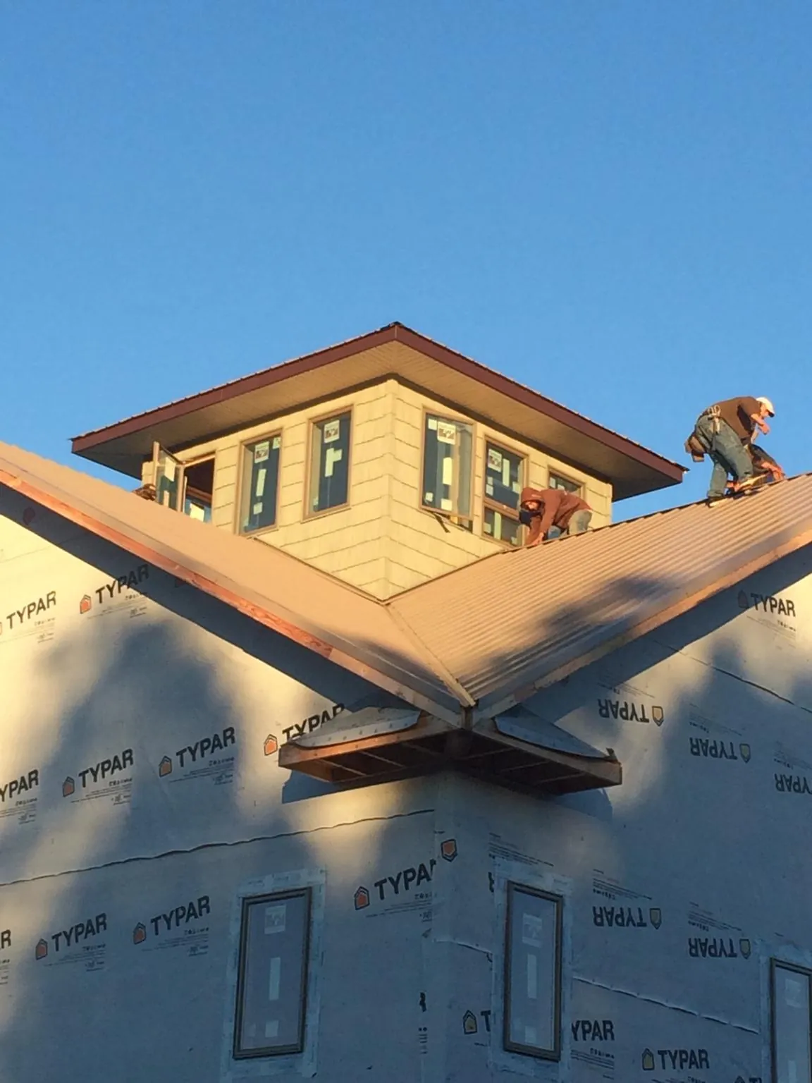 Roofers working around a rooftop cupola on a new metal roof at sunset — Roof Waterproofing in West Babylon by Roofing Brothers